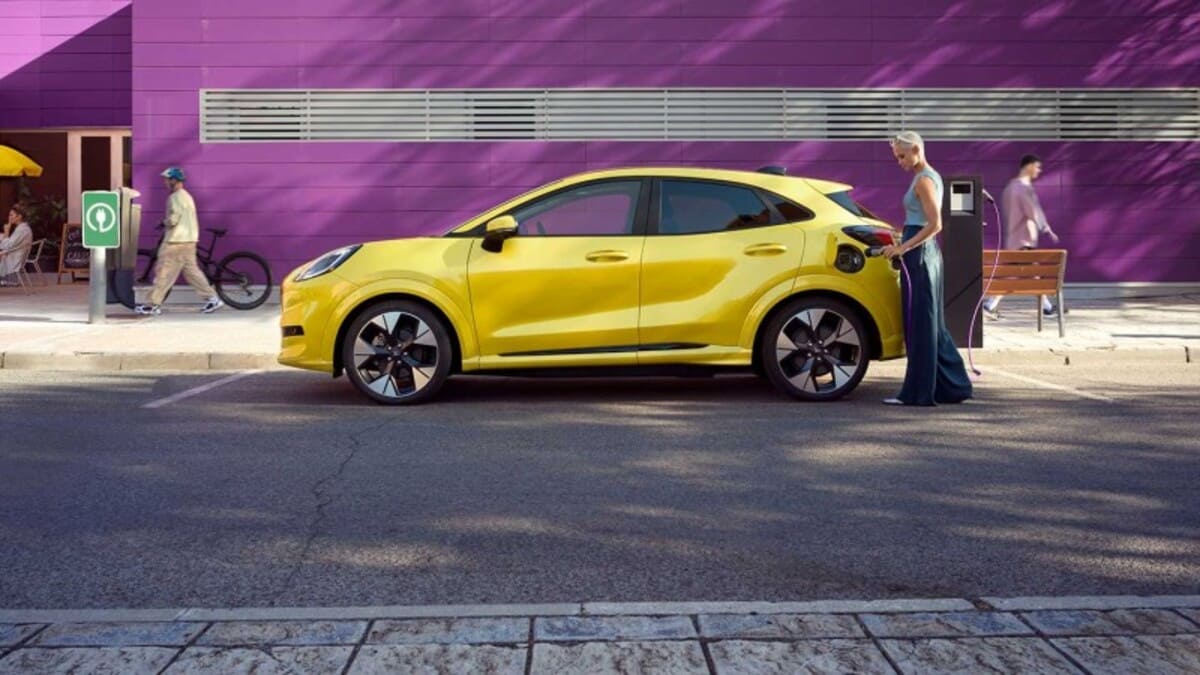 femeie care alimenteaza la statia de incarcare electrica un Ford Puma galben 